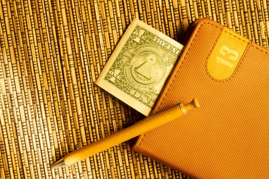 One dollar in a notebook with pen on wooden bamboo background. money as a bookmark. financial background