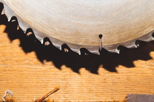 Metal circular saw blade on a wooden background. top view. work tool. carpentry instrument