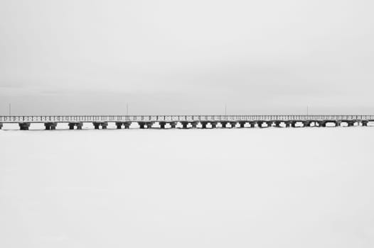 Bridge on the frozen lake. long footbridge dividing the horizon. conceptual minimalistic image. black and white background with copy space
