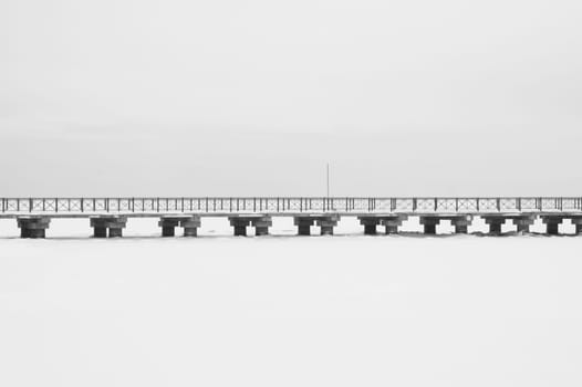 Bridge on the frozen lake. long footbridge dividing the horizon. conceptual minimalistic image. black and white background with copy space