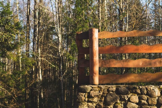 Trees in the park. wooden fencing and natural stone wall. nature background