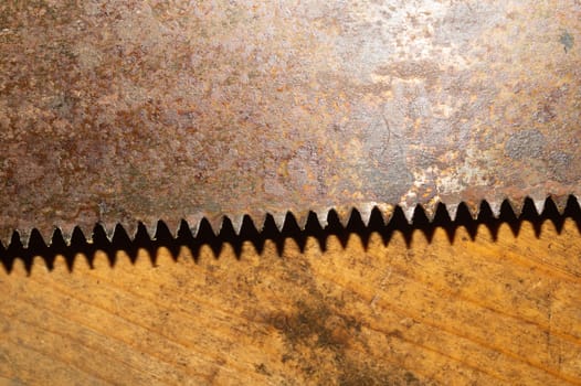Old hand saw on a dirty wooden background. working area with hand tool. carpentry instrument. manual labor concept
