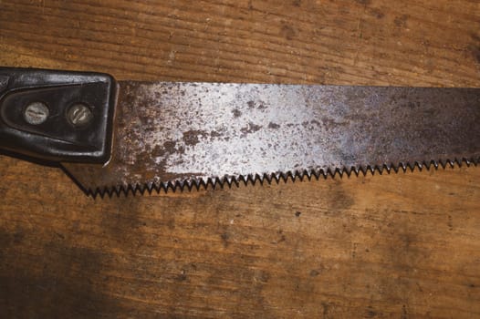 Old hand saw on a dirty wooden background. working area with hand tool. carpentry instrument. manual labor concept