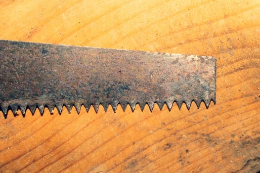 Old hand saw on a dirty wooden background. working area with hand tool. carpentry instrument. manual labor concept