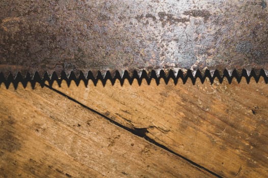 Old hand saw on a dirty wooden background. working area with hand tool. carpentry instrument. manual labor concept