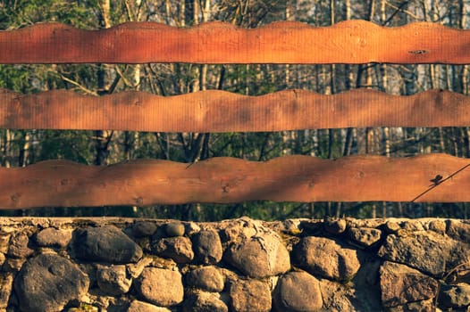 Wood and stone background. wooden fencing and natural stone wall in the park