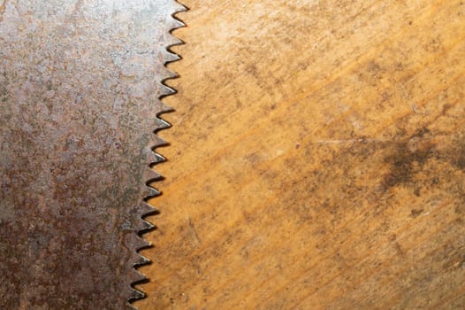 Old hand saw on a dirty wooden background. working area with hand tool. carpentry instrument. manual labor concept