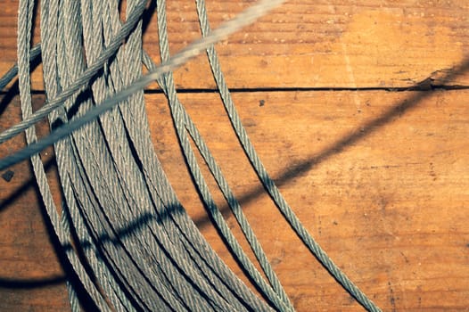 Steel cable on wooden background. hank of metal rope lies on the table. work tool