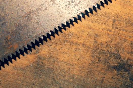Old hand saw on a dirty wooden background. working area with hand tool. carpentry instrument. manual labor concept