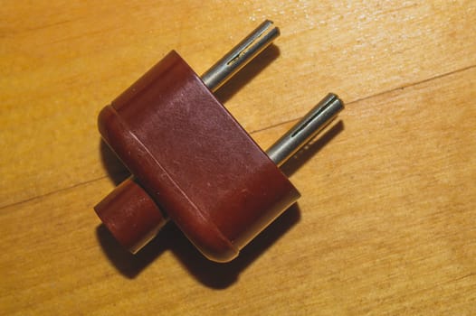 Vintage brown power plug without cord on the wooden table