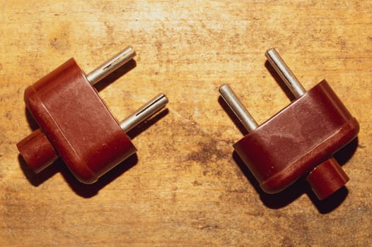 Two vintage brown power plugs without cord on the wooden table