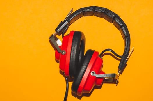 Vintage red headphones on yellow background. retro earphones
