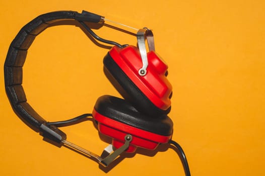 Vintage red headphones on yellow background. retro earphones