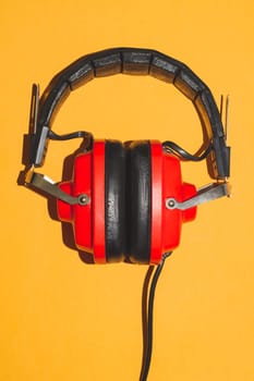 Vintage red headphones on yellow background. retro earphones