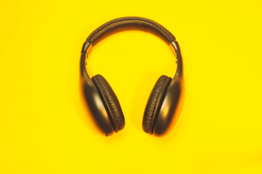 Black headphones on a yellow background. wireless earphones