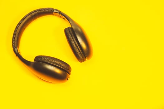 Black headphones on a yellow background. wireless earphones