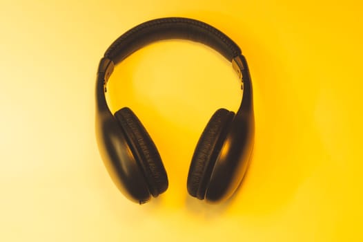 Black headphones on a yellow background. wireless earphones