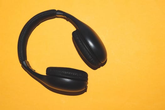 Black headphones on a yellow background. wireless earphones