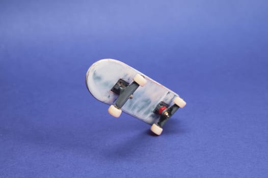 Small skateboard on blue background. tiny skate for fingers. fingerboard close up. home leisure concept. copy space