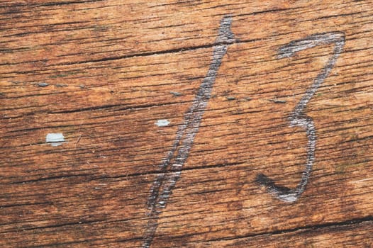 Wood surface with drawn number thirteen. old wooden texture. cracked and scratched background