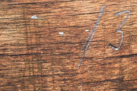 Wood surface with drawn number thirteen. old wooden texture. scratched and cracked background