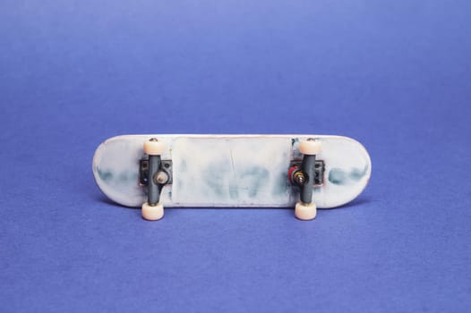 Small skateboard on blue background. tiny skate for fingers. fingerboard close up. copy space