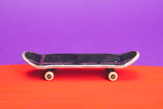 Small skateboard on color background. tiny skate for fingers. fingerboard close up. copy space
