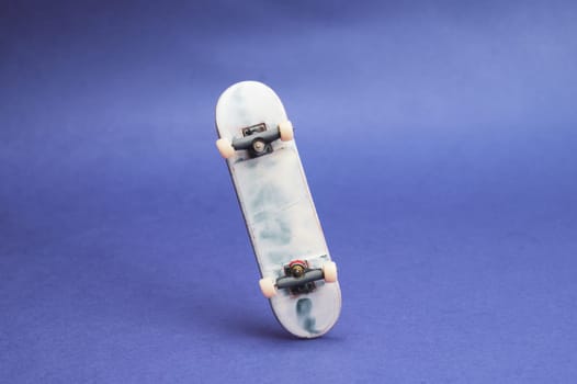 Small skateboard on blue background. tiny skate for fingers. fingerboard close up. home leisure concept. copy space