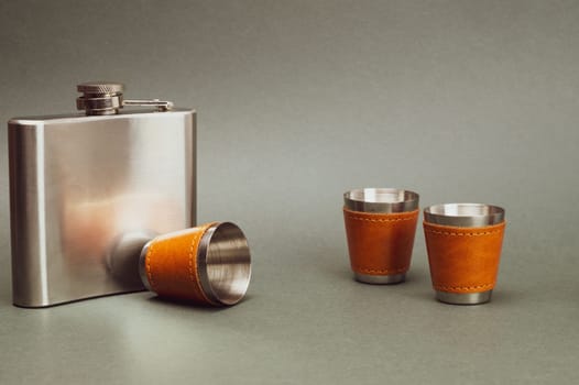 Stainless steel flask. metallic shot glasses. travel shot glass for alcohol with leather casing over the metal. personal accessory set. copy space