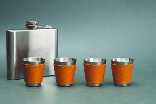 Metallic shot glasses in a row. metal flask. travel shot glass for alcohol with leather casing over the stainless steel. personal accessory set. copy space