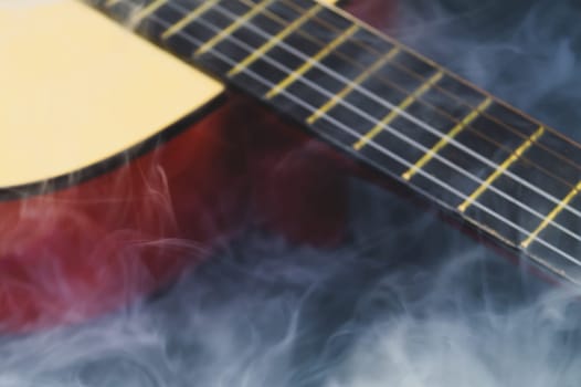 Defocused guitar in smoke abstract background. musical instrument. strings on the guitar fretboard. focus on foreground