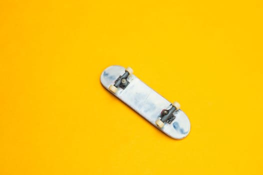 Small skateboard on yellow background. tiny skate for fingers. fingerboard close up. copy space