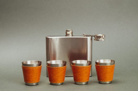 Metallic shot glasses in a row. metal flask. travel shot glass for alcohol with leather casing over the stainless steel. personal accessory set. copy space