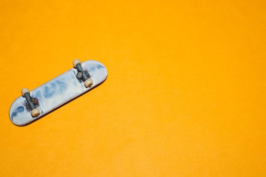 Small skateboard on yellow background. tiny skate for fingers. fingerboard close up. copy space