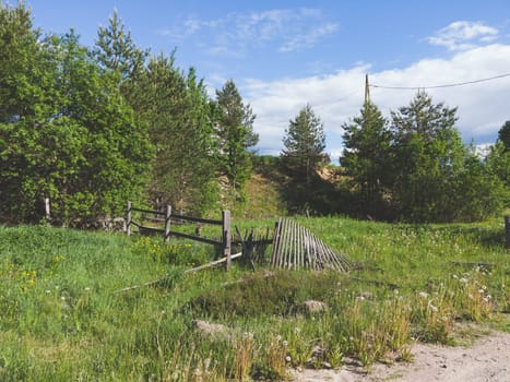 Destroyed wooden fence in countryside. rural landscape. summer day
