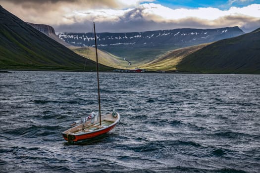 a small boat in front of the mountain coast
