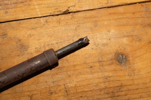 Old rusty soldering iron on wooden table. work tool