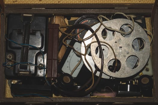 Suitcase with various vintage things. old film reel. multimeters and wires