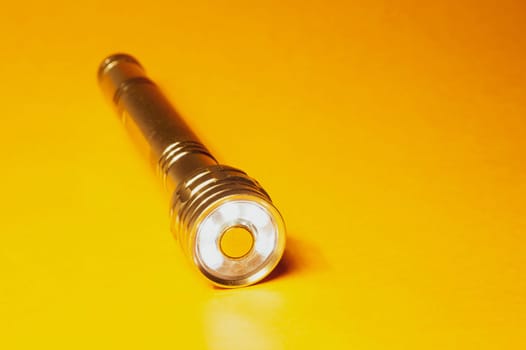 Metal flashlight on a yellow background
