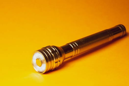 Metal flashlight on a yellow background