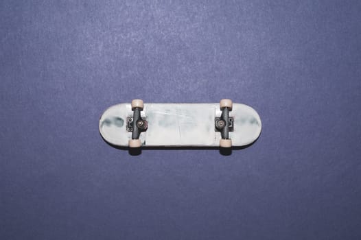 Small skateboard on color background. tiny skate for fingers. fingerboard close up. home leisure concept. copy space