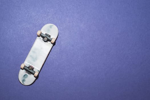 Small skateboard on blue background. tiny skate for fingers. fingerboard close up. copy space