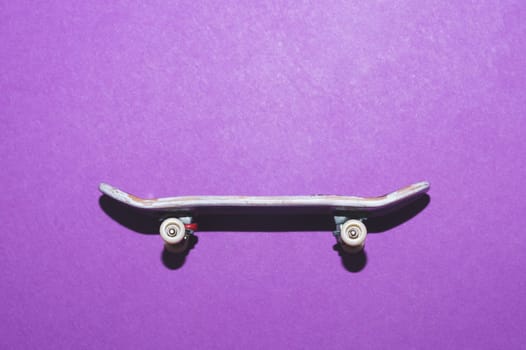 Small skateboard on purple background. tiny skate for fingers. fingerboard close up. copy space