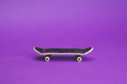 Small skateboard on purple background. tiny skate for fingers. fingerboard close up. copy space