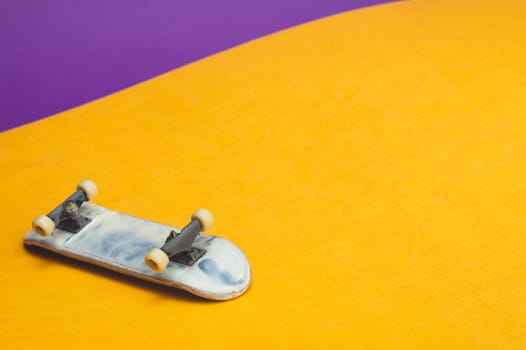 Small skateboard on color background. tiny skate for fingers. fingerboard close up. home leisure concept. copy space