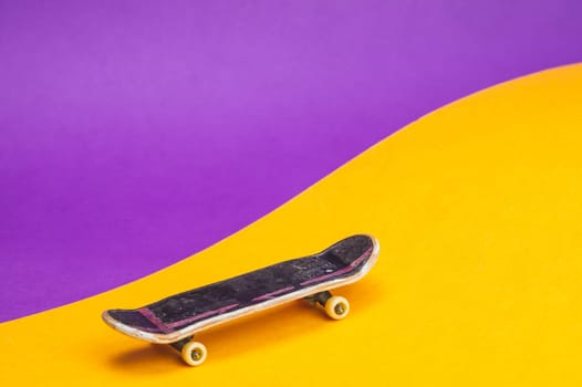 Small skateboard on color background. tiny skate for fingers. fingerboard close up. home leisure concept. copy space