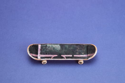 Small skateboard on blue background. tiny skate for fingers. fingerboard close up. copy space