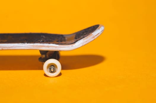 Small skateboard on yellow background. tiny skate for fingers. fingerboard close up. copy space