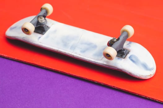 Small skateboard on color background. tiny skate for fingers. fingerboard close up. copy space