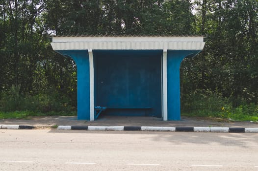 Rural bus stop on the country road with the forest on the background